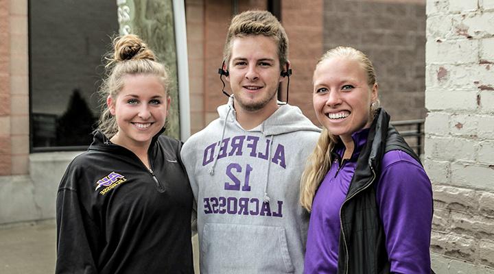 three students smiling together in saxon athletic clothing